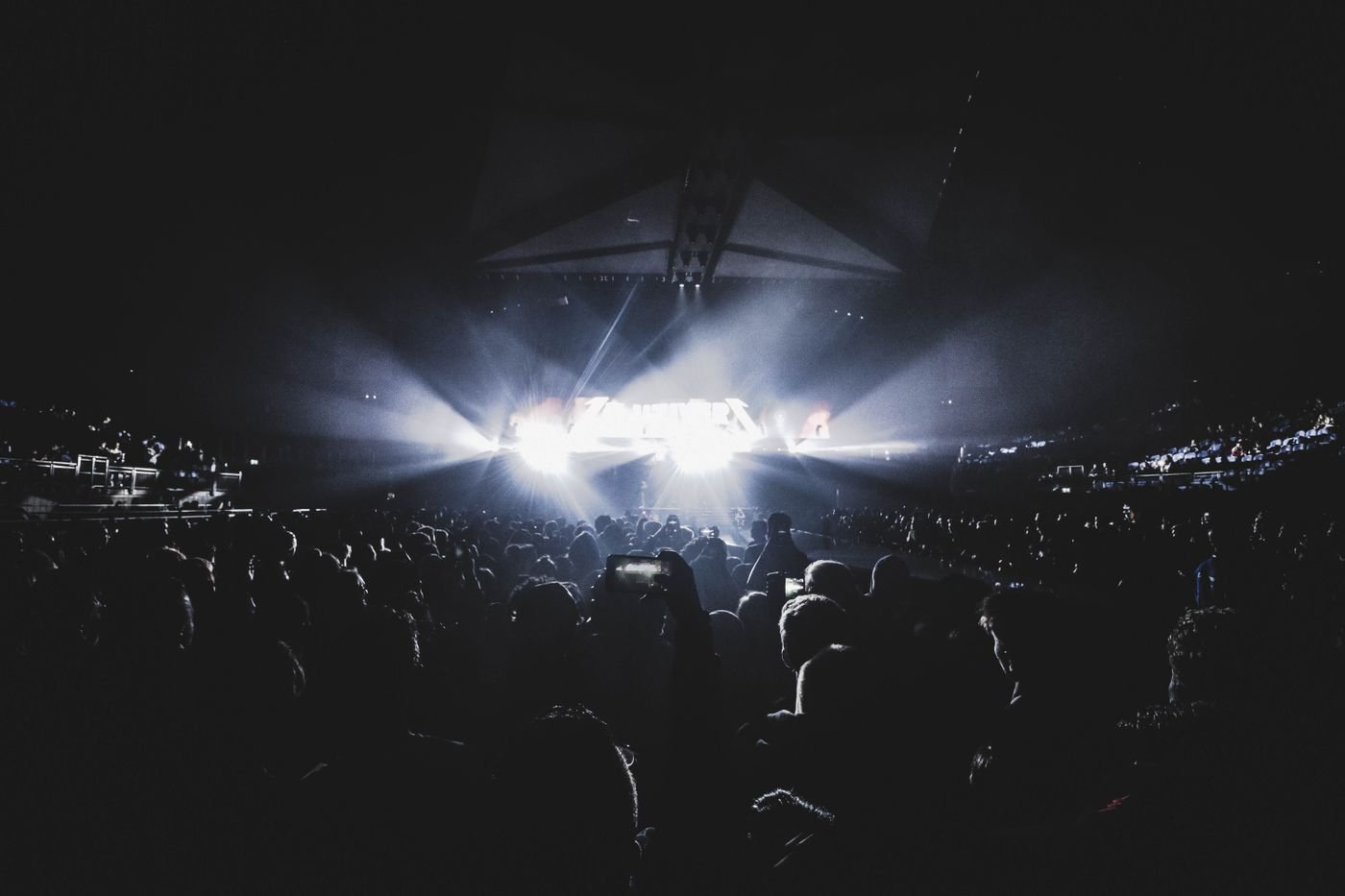 A crowd silhouetted against stage lights in a darkened arena