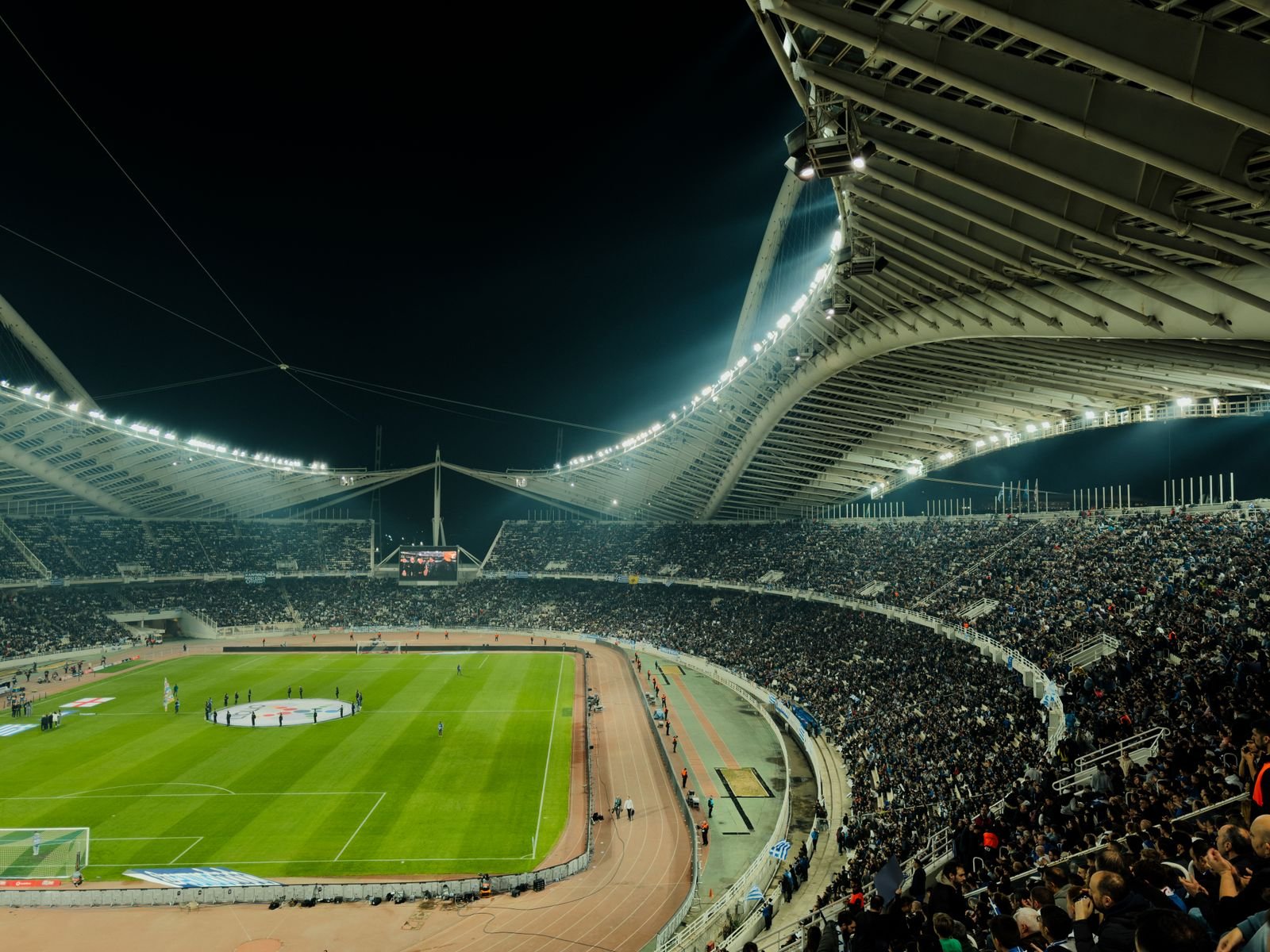 A floodlit stadium at night, filled with spectators